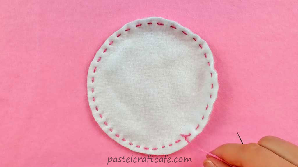 A circle of white fleece with the running stitch sewn along the edge
