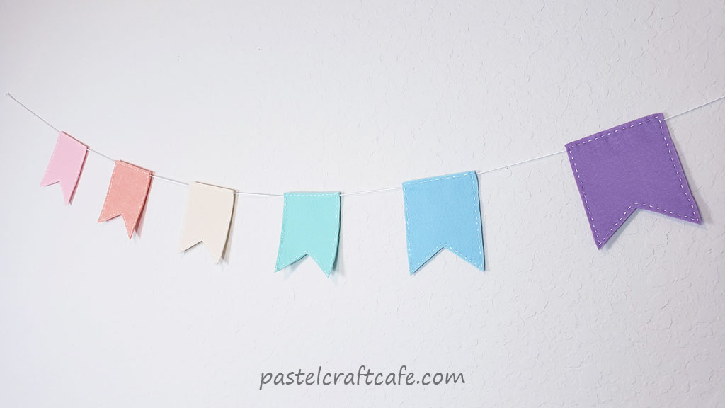A finished pastel rainbow colored flag banner hanging on the wall at another angle