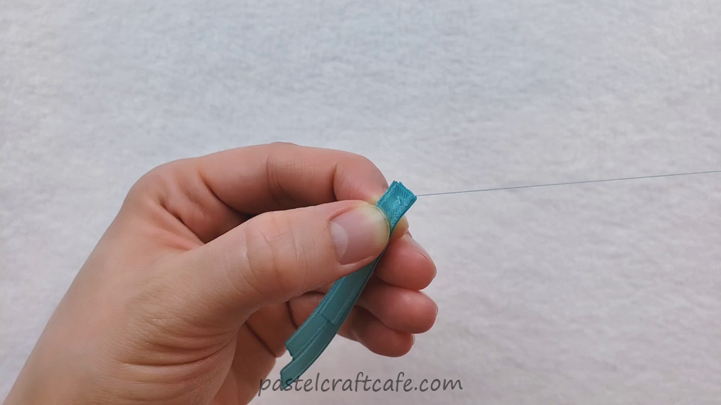 Thread being sewn through the three layers of ribbon