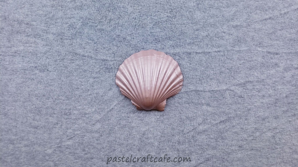 A seashell painted with champagne pink spray paint