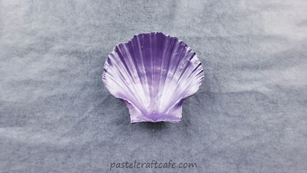 The back of a seashell after four coats of metallic purple paint