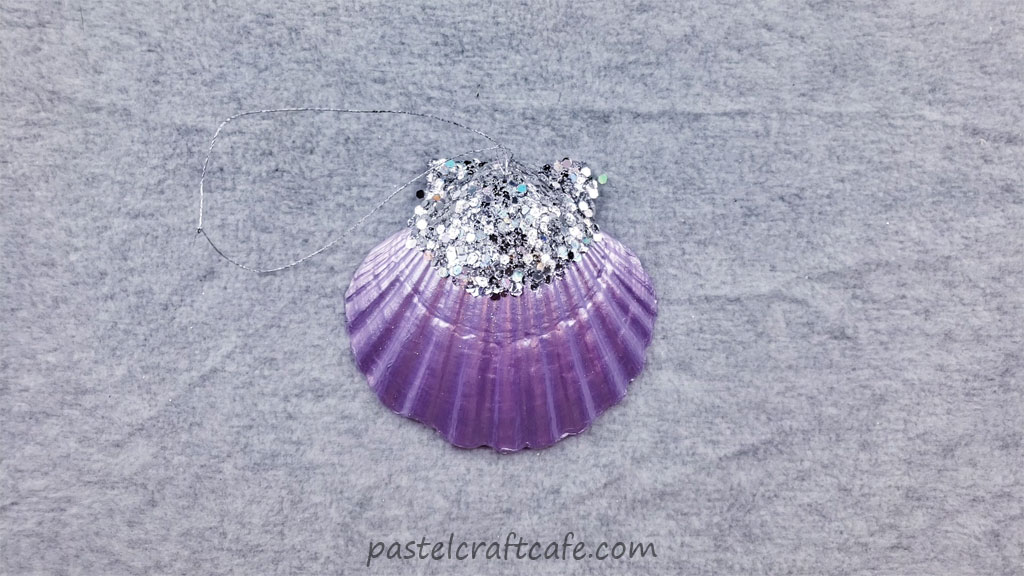 A finished purple glitter seashell ornament with ornament string attached