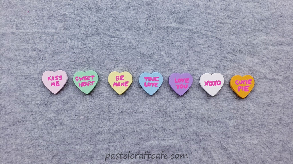 Painted wooden hearts with conversation heart slogans painted in magenta paint