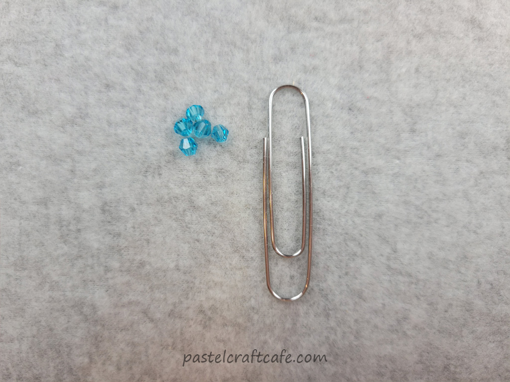 Five 4mm blue glass beads and a paperclip
