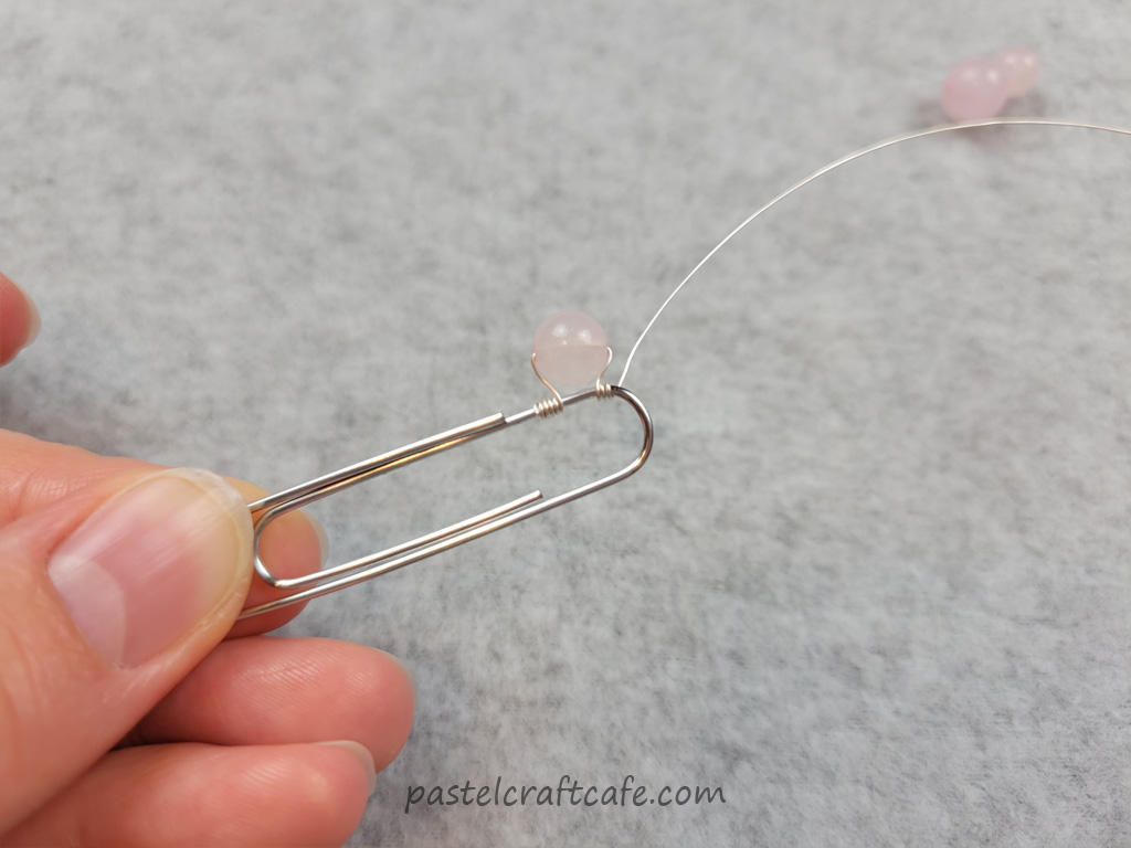 A 6mm rose quartz bead attached to a paperclip with jewelry wire