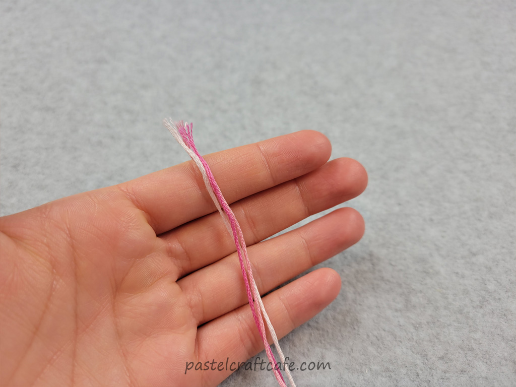Three strands of embroidery floss held next to one another