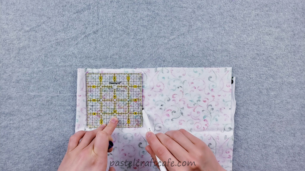 A fabric marker tracing a square onto a piece of flannel fabric