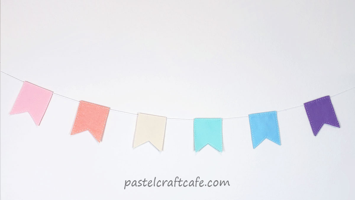 a pastel rainbow banner with flags hangs on a wall