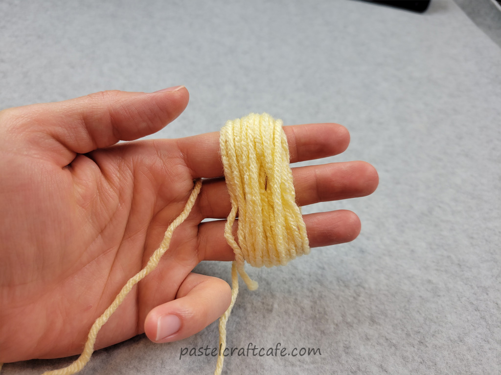 Yarn wrapped around three fingers and the fingers are held slightly apart
