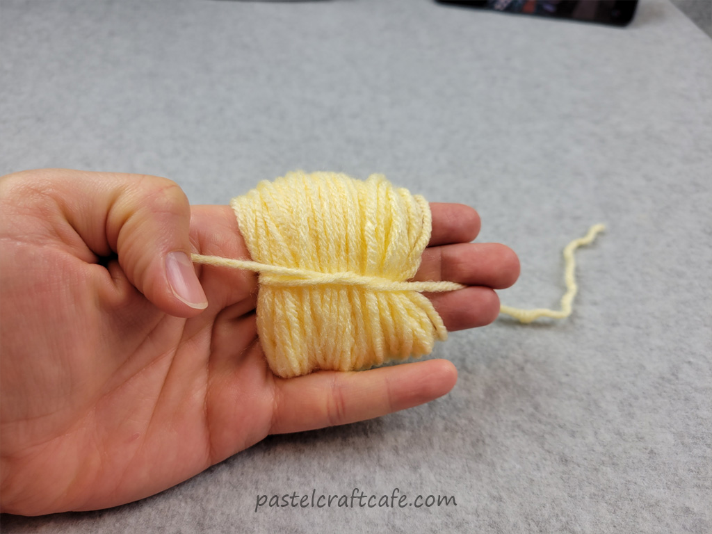 A bundle of yarn around three fingers tied together with another piece of yarn