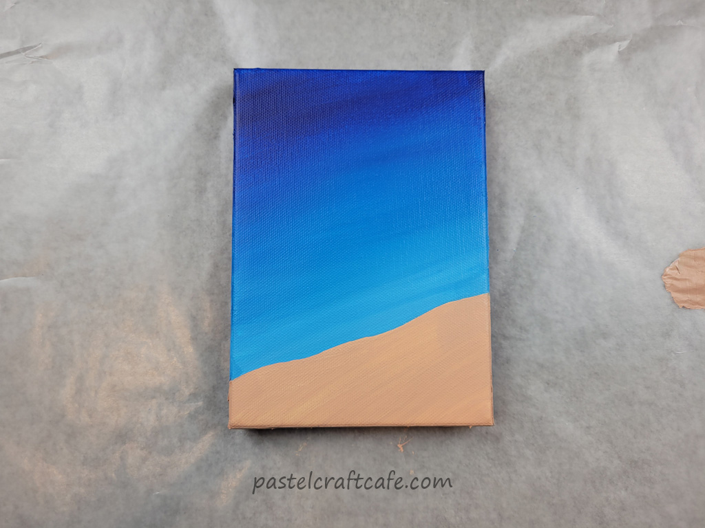 A canvas painted with a blue gradient at the top and tan at the bottom