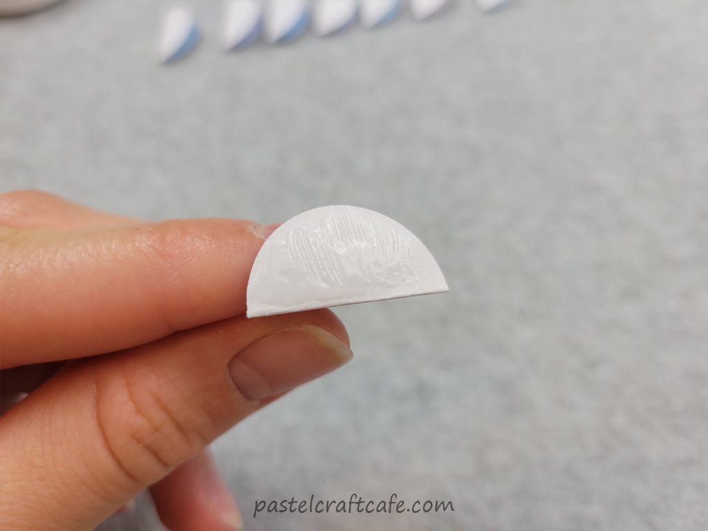 A folded circle of paper with glue brushed on one side