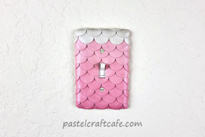 A pink mermaid scale light switch color attached to the wall