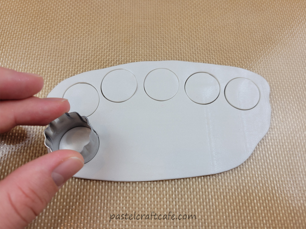 Using a circle fondant cutter to cut circles in white clay