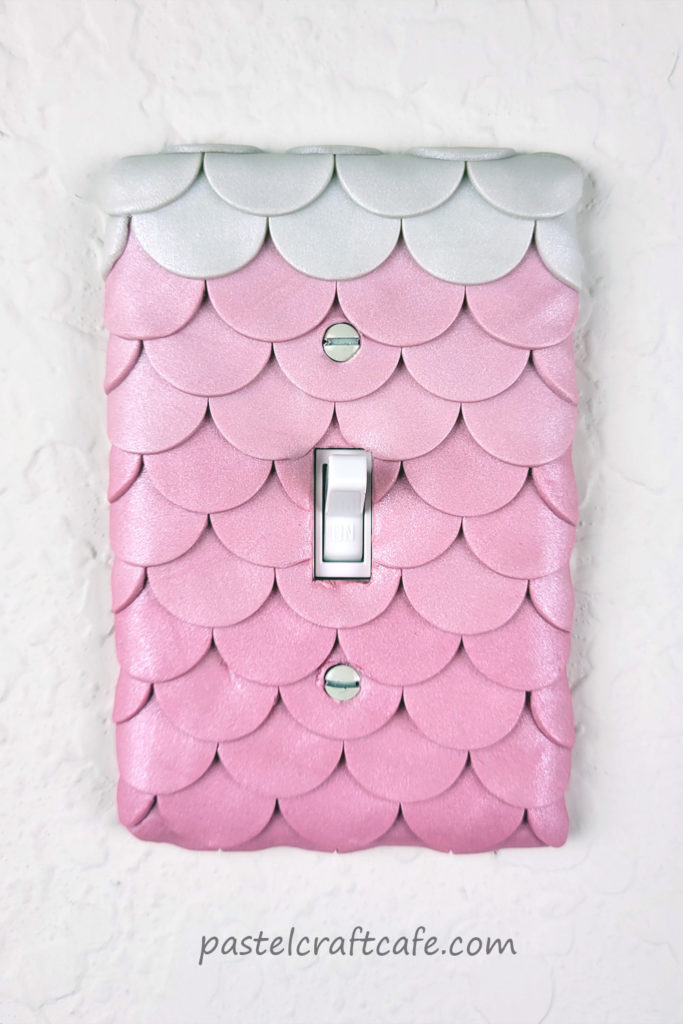 A mermaid scale light switch cover attached to the wall