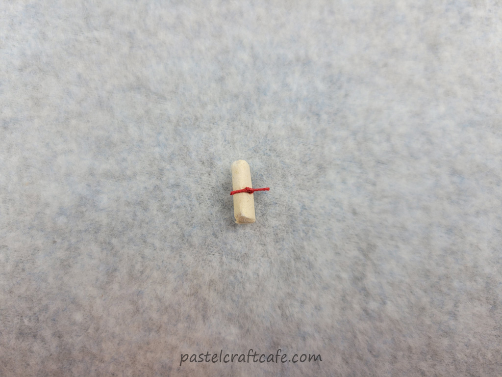 A tiny rolled paper message tied with a small red thread