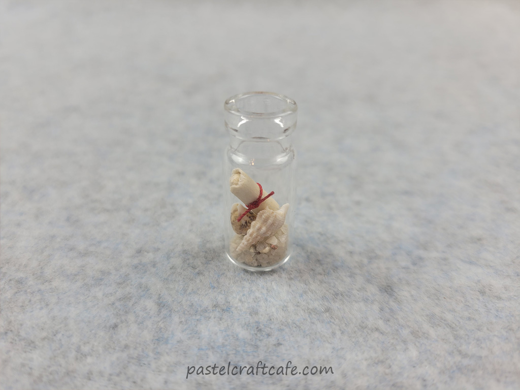 An open message in a bottle with sand and seashells