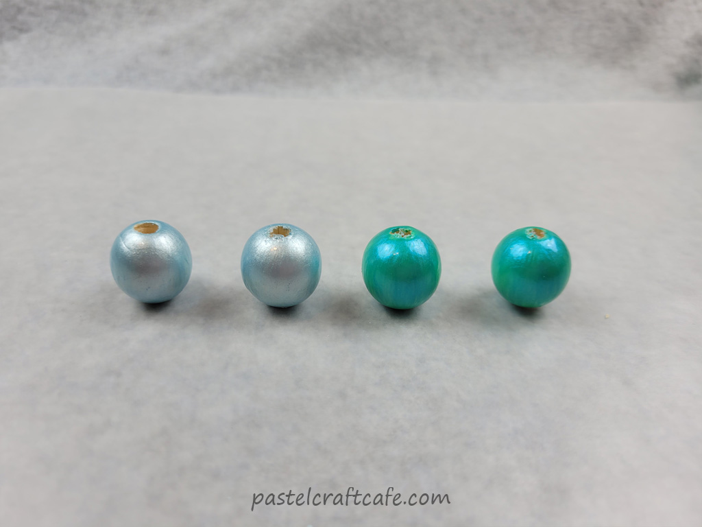 Four finished wooden beads, two painted blue and two painted green