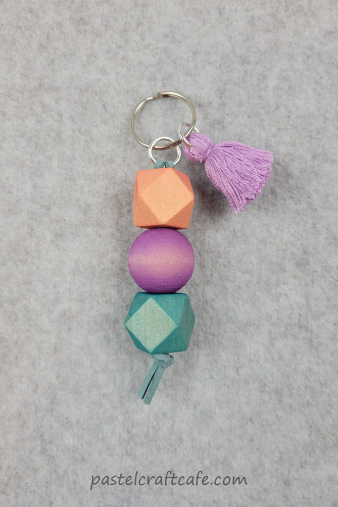 A finished wood bead keychain with dyed beads and a tassel charm
