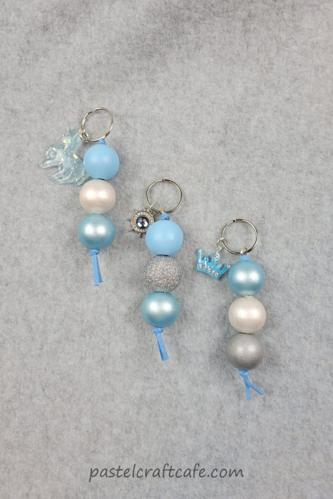 Three finished wood bead keychains with various beads and charms, mostly blue