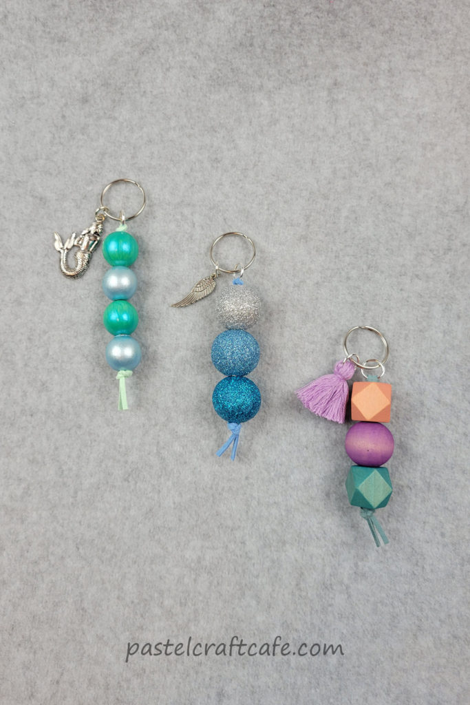 Three finished wood bead keychains, one with painted beads, one with dyed beads, and one with glittered beads