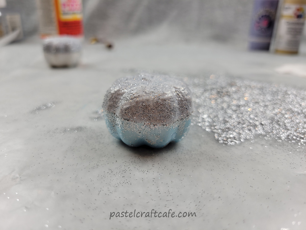 A layer of mod podge sealing in the glitter on a craft pumpkin