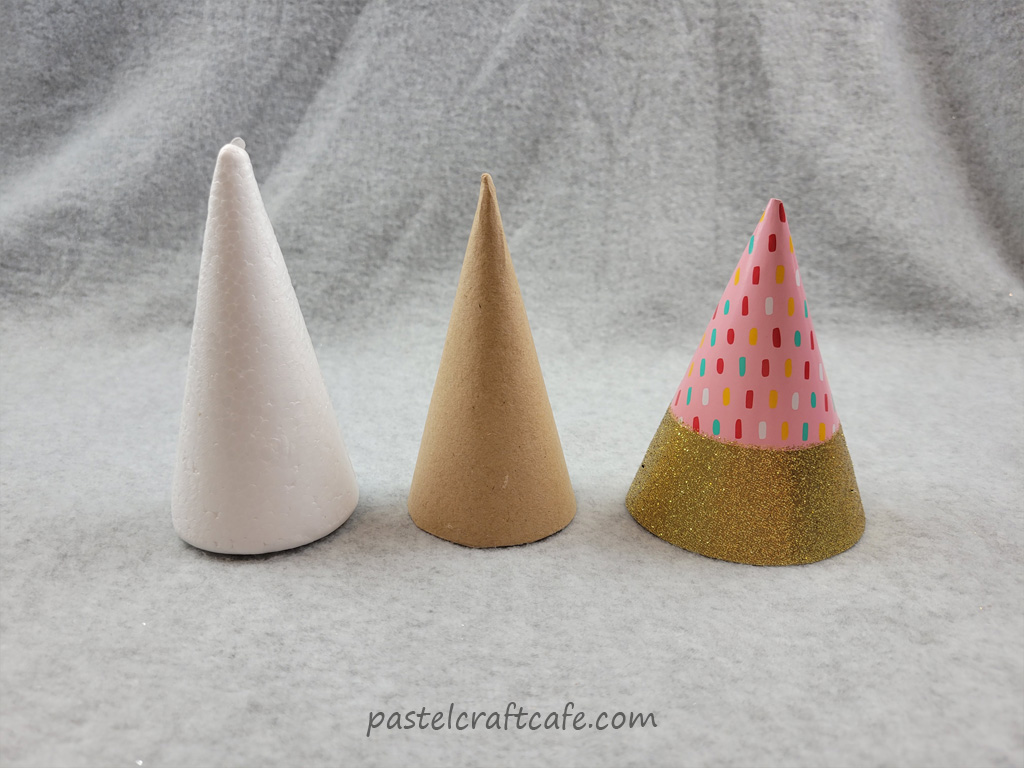 A styrofoam cone, paper mache cone, and a party hat lined up in a row