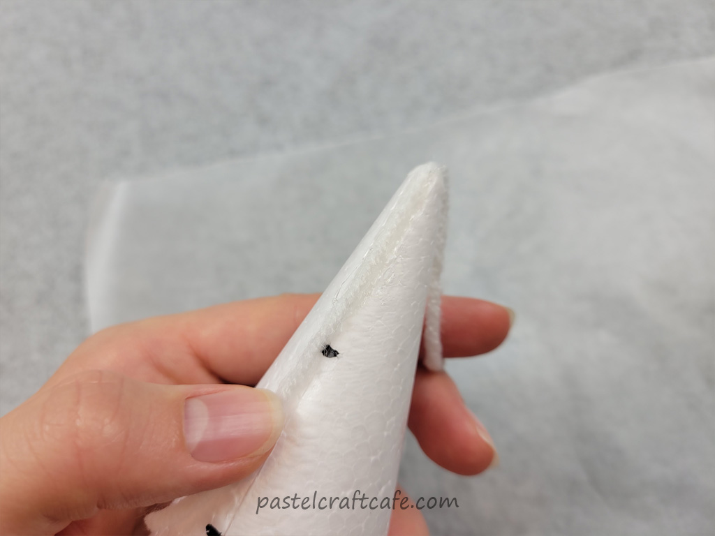 A piece of white yarn glued to the top of a styrofoam cone