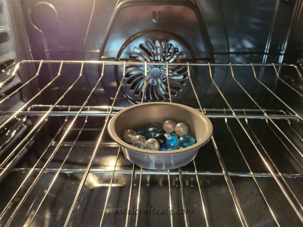 Marbles in a round metal pan sitting in the oven