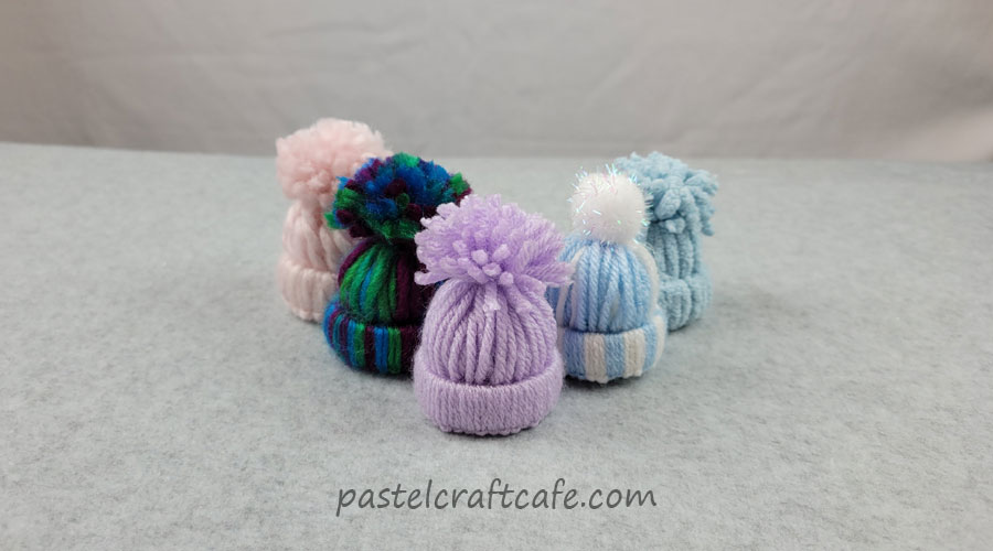 A set of various mini yarn hats arranged in a V shape