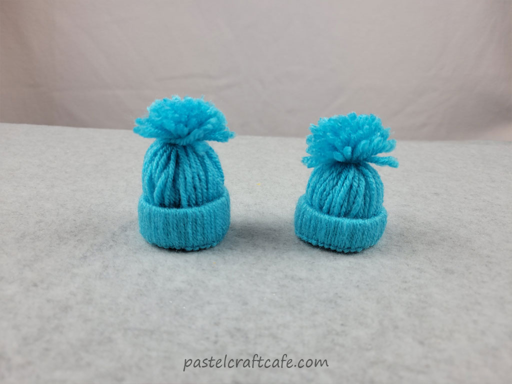 Two mini yarn hats made with the same blue yarn but they have different brim widths