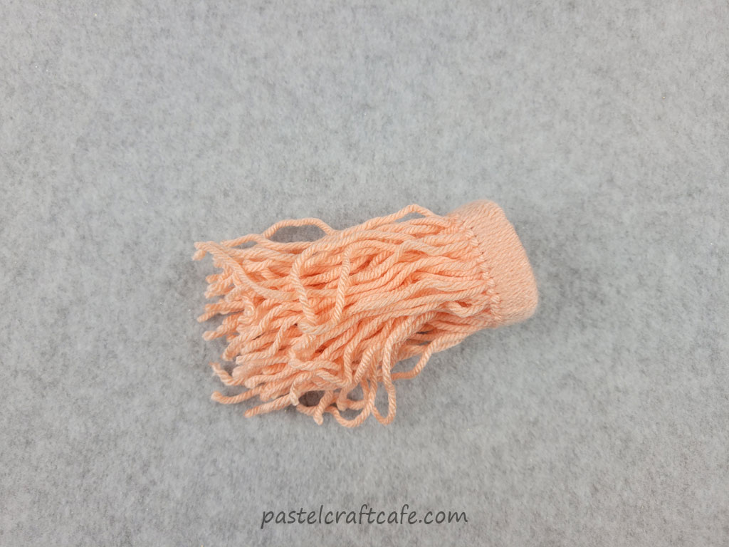 Orange yarn knotted around a toilet paper tube ring