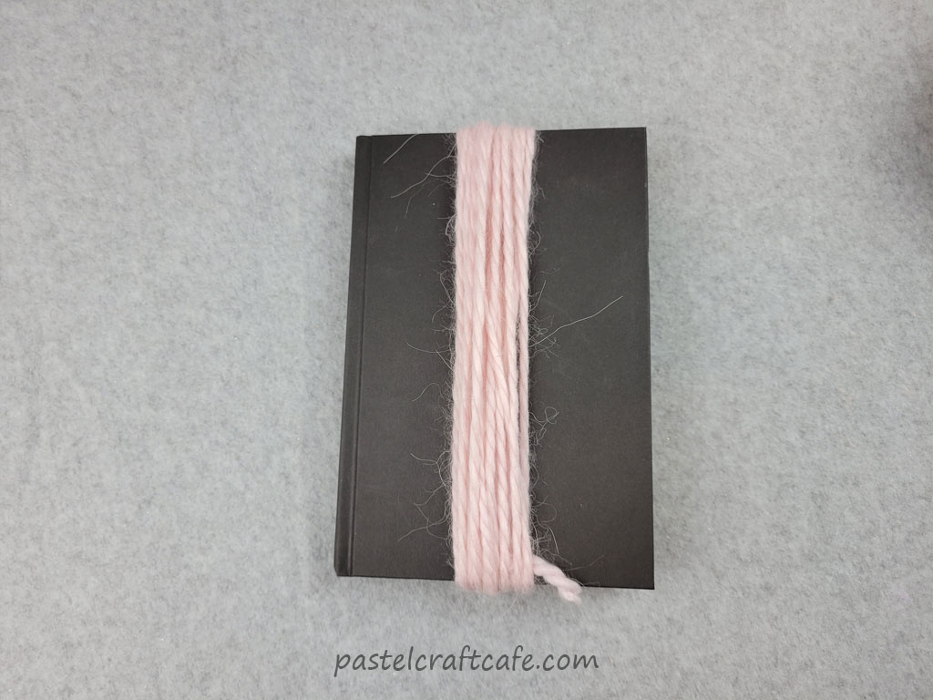A black book with pink yarn wound around it