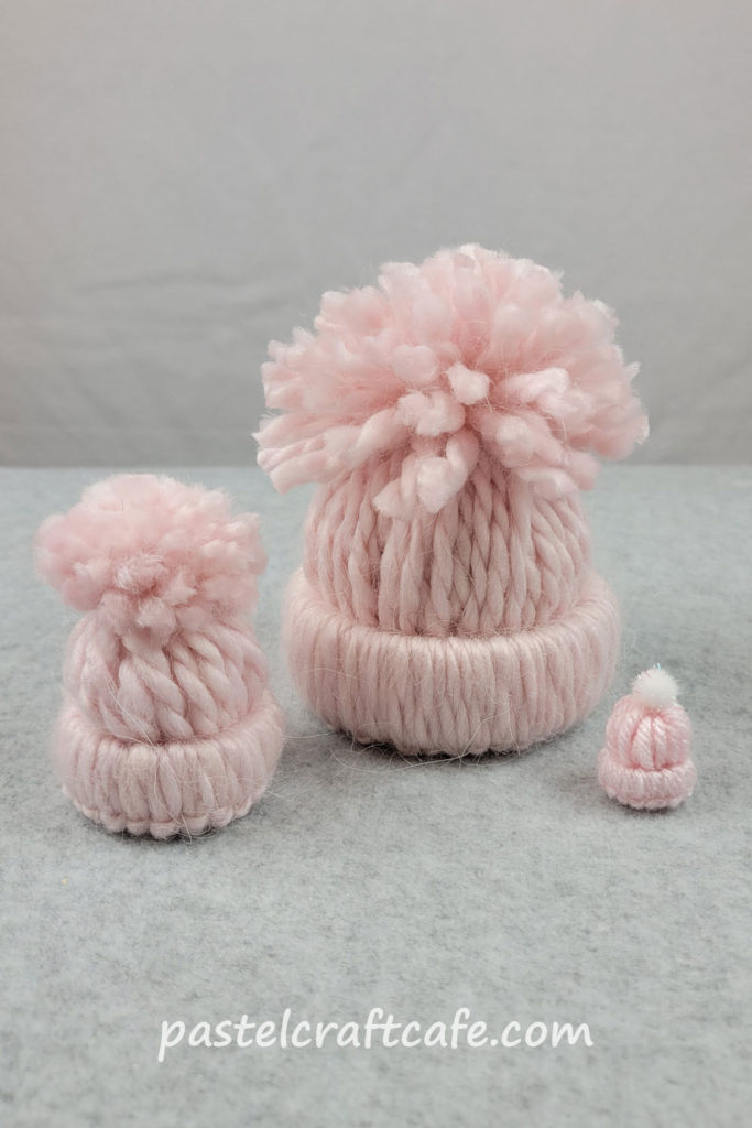 Three pink mini yarn hats in different sizes