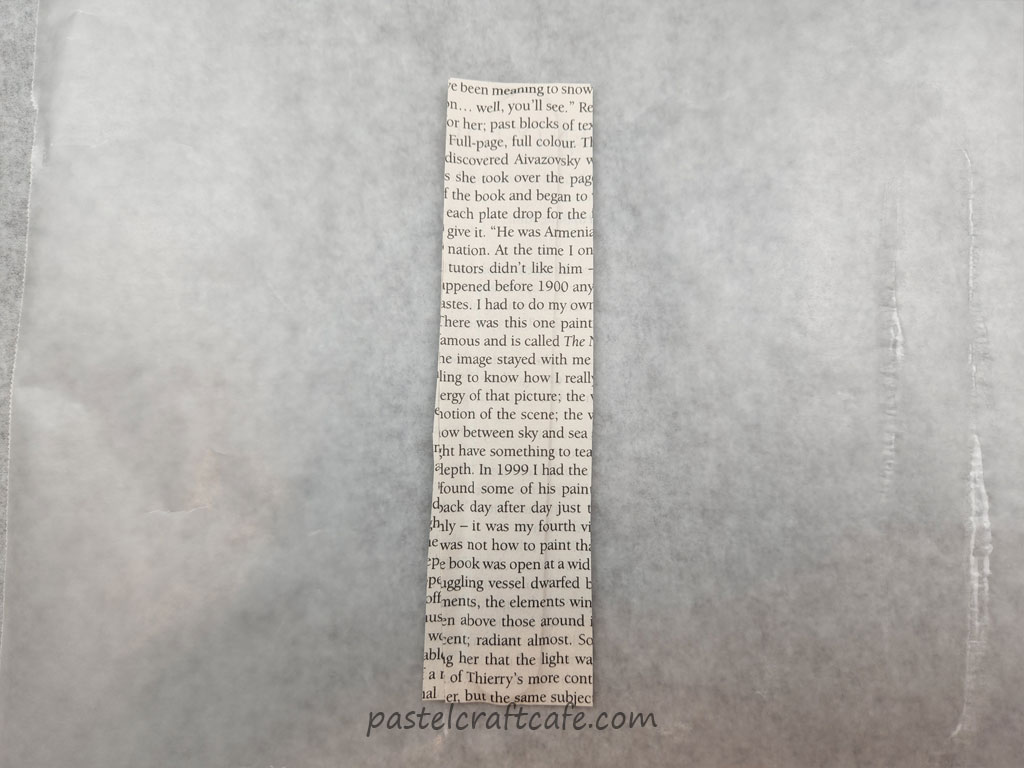 A popsicle stick after pieces of book pages have been glued to both sides