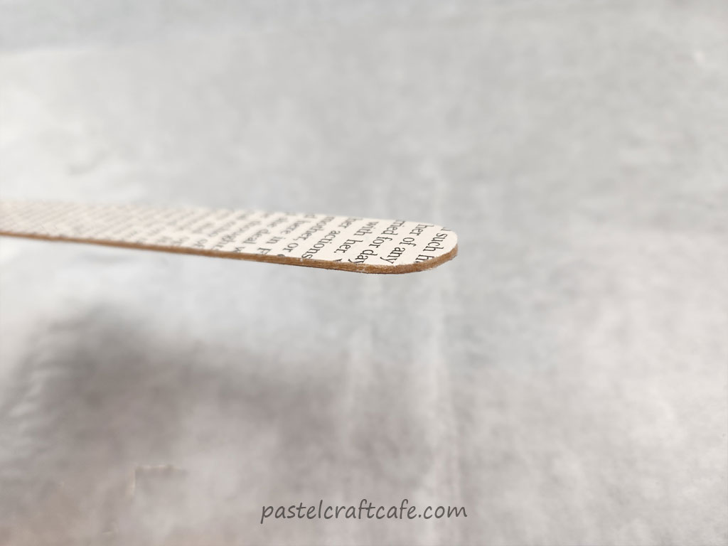 The end of a paper popsicle stick bookmark after sanding down the paper