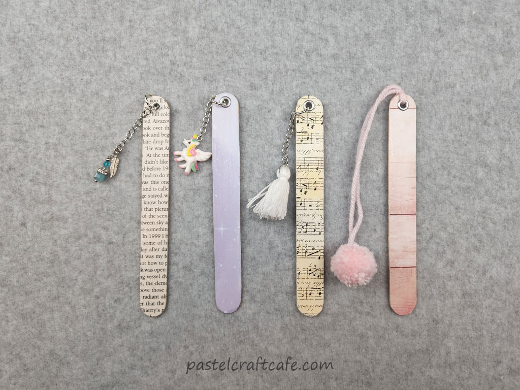 Four finished paper popsicle stick bookmarks, each with a different print and embellishment