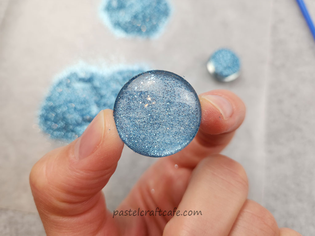 The front side of a cabochon after the second layer of glitter had been applied while the glue was still wet
