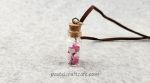 A bottle necklace filled with tiny paper hearts in light pink, dark pink, and white